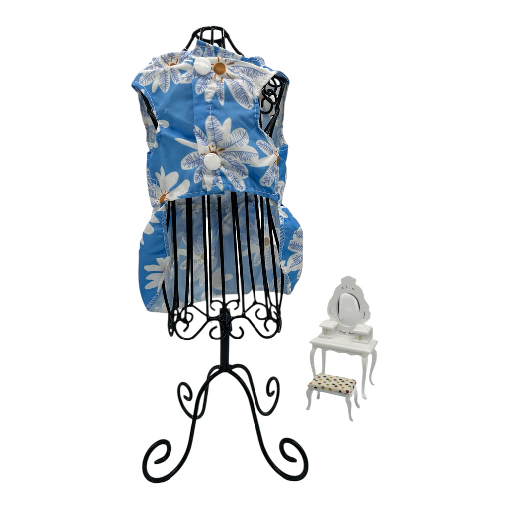 Blue floral cat dress on a black mannequin with a white chair in the background