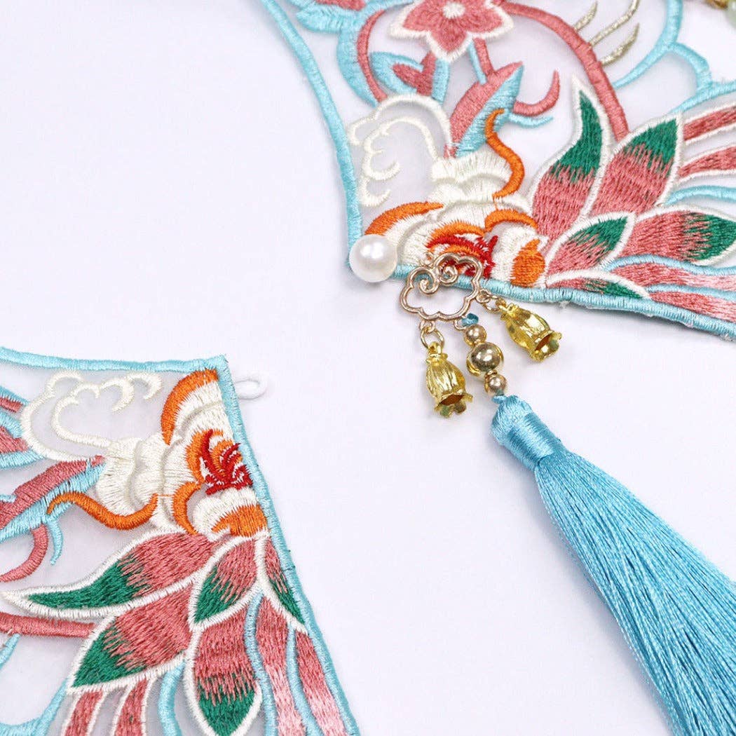 Decorative item with floral embroidery, tassel, and beads on a white background