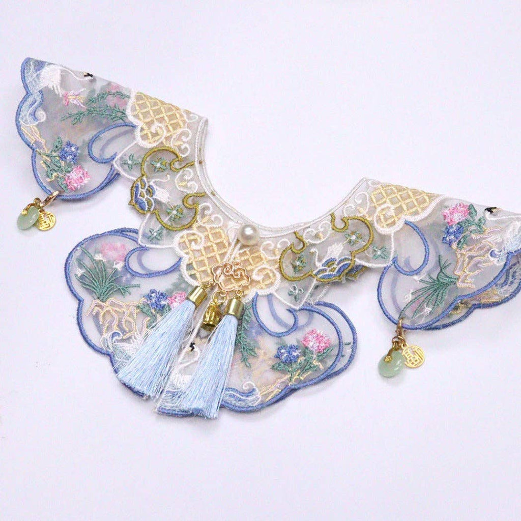 Decorative cat collar with floral patterns, tassels, and gold accents on a light background