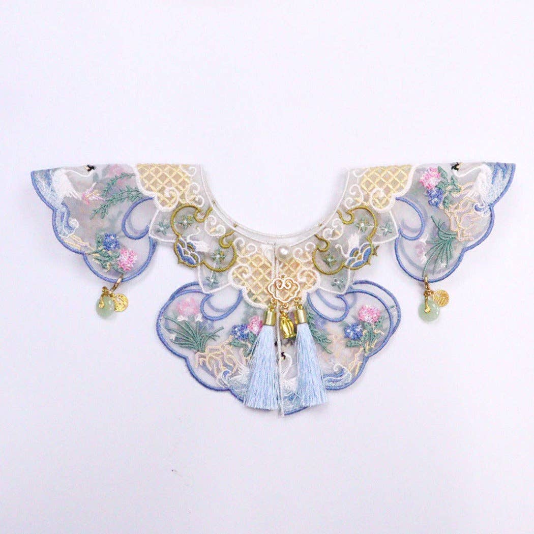Decorative cat collar with floral patterns and tassels on a white background