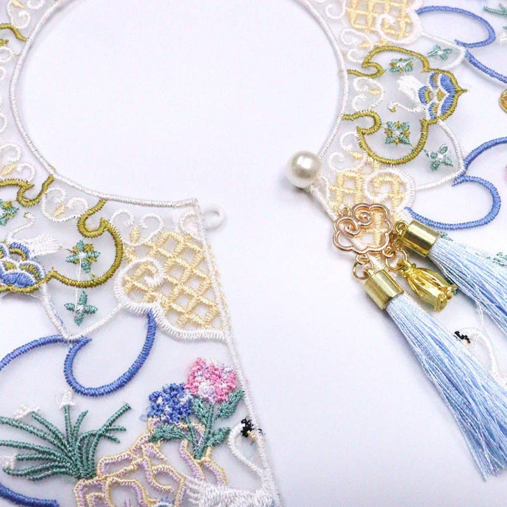 Embroidered decorative cat collar with floral patterns and tassels on a white background